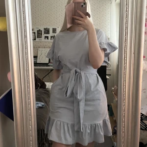 Klänning med volang - En superfin ljusblå klänning med volanger och knytning runt midjan från H&M i strl 34!💓
