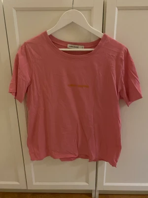 Tshirt - Rosa tshirt med orange text från Carin Wester.