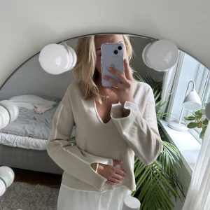 Beige stickad tröja - Beige stickad tröja från NA-KD med slita på armarna och v-rigning på bysten. Använd 2 gånger så i princip nyskick. Storlek xs, nypris 549kr.
