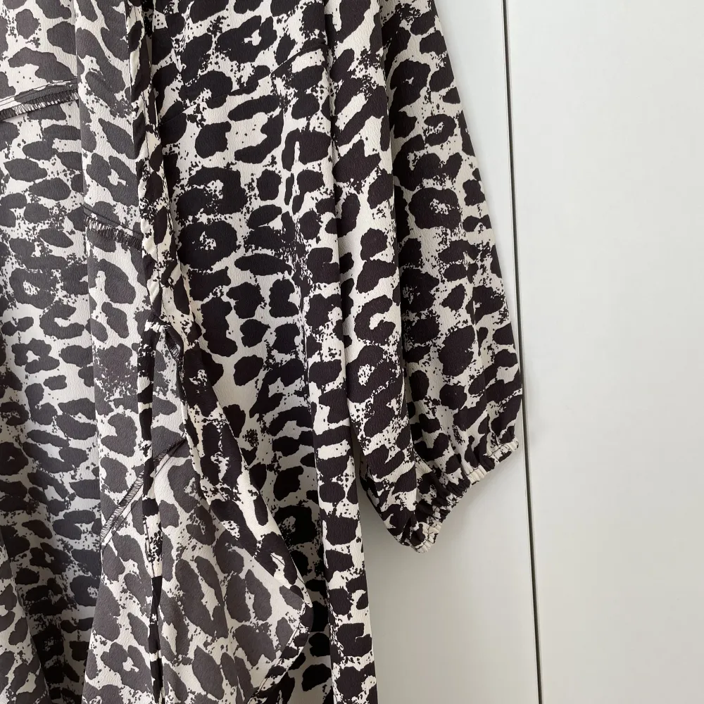 Lång leopardklänning med omlott och volang. Klänningen har långärm. . Klänningar.