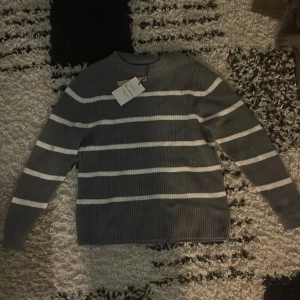 Grå randig stickad tröja bondelid  - Helt ny grå,vit randig stickad tröja från bondelid. Aldrig använd, prislapp kvar. Orginal pris 700kr 