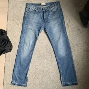 Blåa jeans med slit längst ner. Oklart vilken storlek det är men skulle säga L.