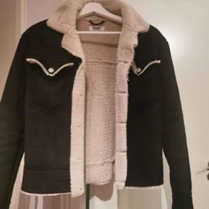 Svart jacka från Nelly - Snygg varmfodrad jacka med mockaliknande känsla på utsidan. Strl 34 men passar även 36. Allt material är faux. Från Nelly. Jackan är i nyskick och knappt använd. 