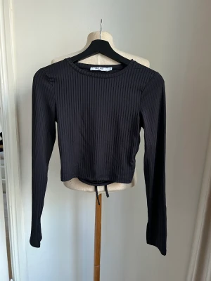 Långärmad topp med öppen rygg NA-KD - Svart långärmad ribstickad topp med öppen rygg med snörning från NA-KD.