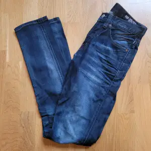 Blå skinny jeans med knappgylf. Färgen ser mer ut som de första bilderna. W 25, L 32.