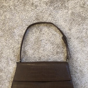Brun väska - Jätte fin brun vegansk axelväska från monki!🤎 andvänd fåtal gånger och är i väldigt bra skick med inga defekter, säljer då den inte kommer till användning. Skicka privat för mer bilder!