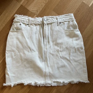 Jeanskjol sliten look  - Benvit jeankjol med sliten look från NAKD. Nån enstaka liten noppa i tyget men annars fint skick. Lapp bortklippt men ca storlek 40 (midja 39cm)
