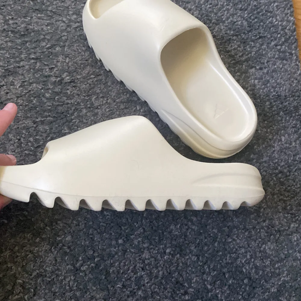 Fick ett par yeezy slides i färgen ”bone” , som var alldeles för små. US 6 strl Äkta men Har ingen box, drf kan sälja billigare. . Kengät.