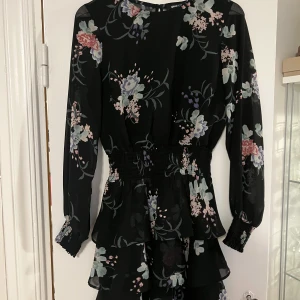 Blommig svart klänning - Blommig svart klänning i väldigt bra skick från ginatricot. Skönt material som är perfekt för sommaren. Storlek 34 funkar som 36.