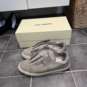 Axel Arigato skor - Gråa Axel Arigato skor i okej skick. Inte använda på ett tag. Skorna är i strlk 39 men sitter lite stort och är lite uttöjda.