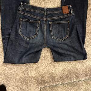 Säljer mina mörkblå lågmidjade utsvängda jeans ifrån de.corp 🩷 Jag är 160 och dem passar ungefär perfekt, storlek 27/32. Jag har använt dem ett fåtal gånger och mest under vintern då dem blev lite utslitna men annars är jeansen i ett bra skick. 