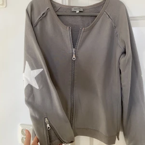 Hunkydory kofta - Tröja från hunkydory essentials med dragkedjor, kan användas på flera olika sätt. Stjärnor på armbågarna. S/M
