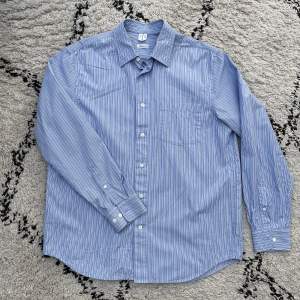 Relaxed skjorta i bomullspoplin i blå randigt mönster. fint skick använd få gånger.