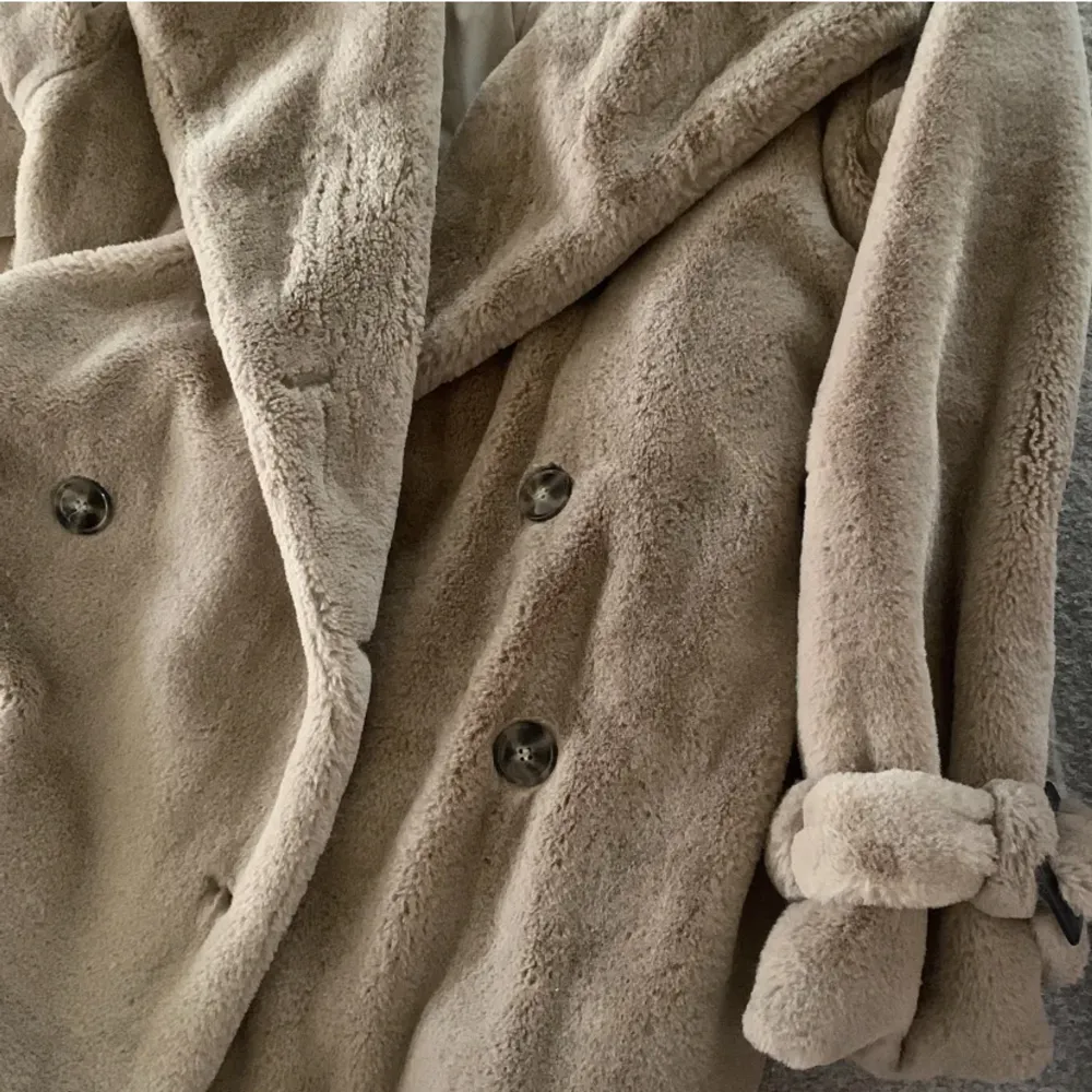 En beige längre kappa i mjuk ”päls” från NAKD (HannaLicious kollektion) 🫶🏼bälte i midjan, fickor och knappar, helt perfekt höst/vinter kappa! Jättefint skick ✨. Jackor.