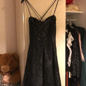 Svart Festklänning - Jättesnygg svart festklänning av spets med paljettbyst och korsad rygg. aldrig använd 