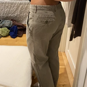 Grå / gröna byxor. Chinos material.  - Chinos, litet hål på baksidan som är lagat. Syns knappt. 