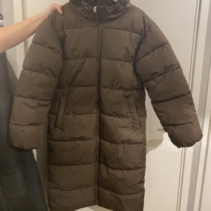 Pufferjacka - Säljer denna bruna Pufferjacka från NAKD i storlek 32. Dock stor i storlek, passar mig som är 170 cm lång bra. Knappt använd 