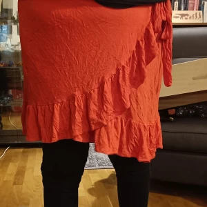 Röd omlottkjol  - Röd omlottkjol, som man knyter själv. Knappt använd. Ca 50cm lång.