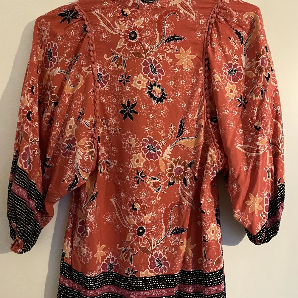 Söt topp med fransar, och brodyr. I bra skick och tunnt material. Trekvartsärmar med lite puff. Knappar vid kragen.. Puserot.