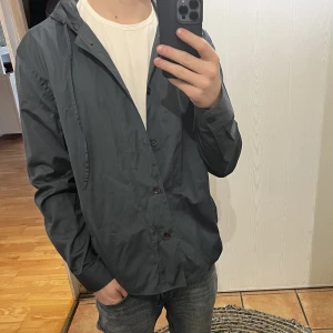 Filippa K hoodie/overshirt - Helt ny Filippa K hoodie med knappar i ett tunt material. Den är i nyskick och slm gott som aldrig använd! Den är storlek 50 och passar väldigt bra på mig som 178 cm lång!