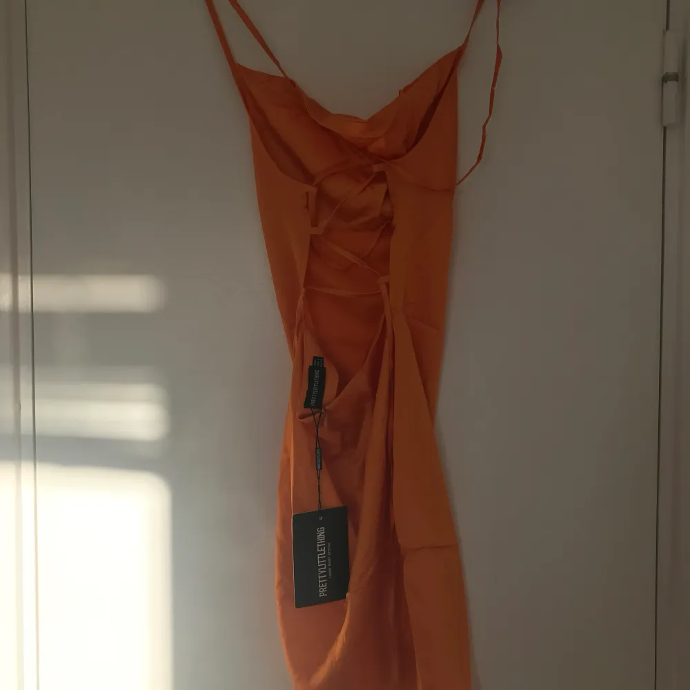 Orange kort satinklänning från PLT med öppen/smörad rygg. Aldrig använd, endast provad, lappar kvar. Klänningar.