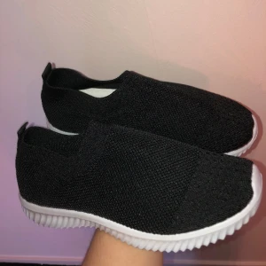 Svarta sneakers i stl 38 - Dessa svarta sneakers är i tunt material och är därför perfekta för sommaren och våren. Dem är aldrig använda och är i nyskick.