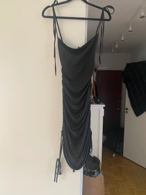 Klänning - Svart figurformad klänning med snörning vid axlar och ben