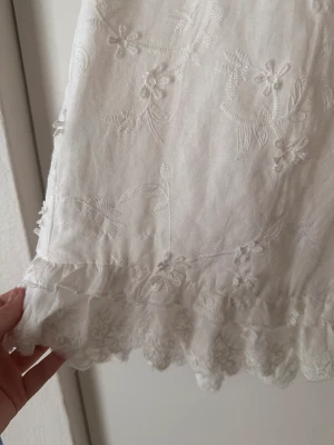 Fantastisk studentklänning - En jättefin studentklänning. Volang längst ner, fint sydd vid halsen. Öppen rygg. Blommor sydda på. Bara testad!