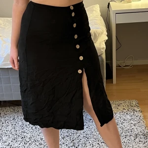 Svart kjol med knappar - Tunn jättefin kjol från HM! Perfekt till sommaren. Är i storlek 34 men skulle säga att den passar en 36a också. (Jag själv är en 36/38) 🥰