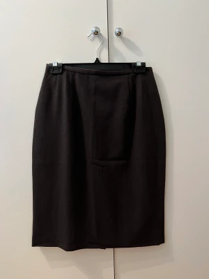 Kjol - Brun kjol med dragkedja och slits baktill, med tjockare tyg. Finns tillhörande kavaj utslag på min sida. Märke- Ril’s 