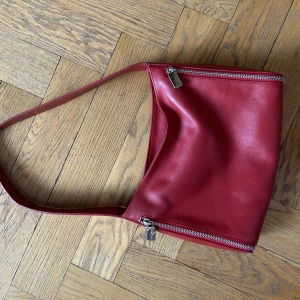 Röd väska  - Röd väska köpt second hand, i super bra skick och använd sparsamt några få gånger. Köp direkt för 95kr eller buda med prisförslag. 