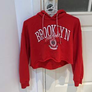 En röd och skön croppad hoodie med tryck. Storleken är ungefär S-M men tröjans lapp säger L. 