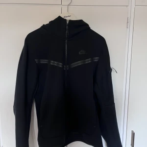 Svart Nike tech - Säljer min svarta Nike tech då jag knappt använder den och tycker den är lite för stor. Den är fortfarande väldigt bra skick!!Nypris 1250kr ish, säljer för 550kr men kan också byta mot en S! Skriv om du har frågor!!!