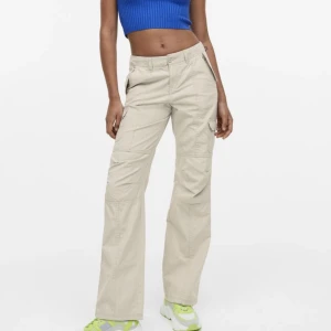 Lågmidjade Cargobyxor - Säljer ett par jättesnygga ljusbeigea lågmidjade cargobyxor men snygga detaljer både back och fram, slutsålda och populära, storlek 32, använda kanske två gånger så nyskick