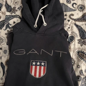 Marinblå Gant Shield Hoodie - 3 år gammal dock väldigt oanvänd.  Inköpspris 1000kr ish. 