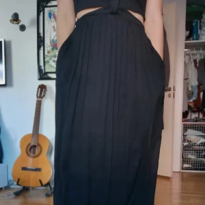 Unik maxikjol av siden med fickor  - Originalpris 2000 kr. Denna kjol har justerbara hängslen. Man kan välja om man vill ha hängslen eller ej. 2 lager så ej genomskinlig. Aldrig använd. Knäpps med blixtlås på sidan