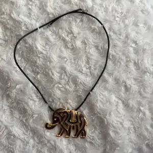 Fint halsband med en guldelefant 
