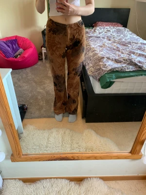 Vintage bruna blommiga byxor  - Coola bruna vintage byxor med blommönster. Köpta secundhand men bra skick! Lagom långa på mig som är 171 cm. Materialet är mjukt och på utsidan lite som mjukisbyxor men modellen ser mer ut som kostymbyxor. Tryck gärna på köp nu knappen.  