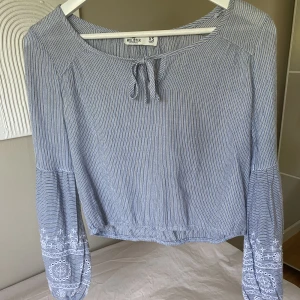 Blus hollister - Supersöt blus från Hollister! Köpt i London och använt sparsamt. Blåvit-randig med spets i ärmarna och knytning vid halsen. Säljer eftersom den tyvärr inte kommer till användning  