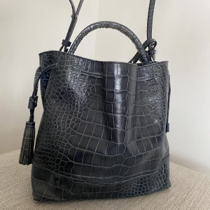 Väska - Säljer denna fina väska i en mörkblå/ mörkgrön nyans. Rymlig väska med ett stort fack och ett lite mindre. Tillkommer frakt på priset💕