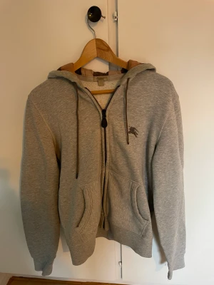Burberry hoodie - Grå burberry hoodie. Storlek S. Säljer billigt för jag haft den rätt länge och den passar inte mig längre. Lite slitage på ärmen vid handleden, inget stort som syns.