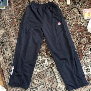Adidas track pants - Jättesnygga Adidas byxor i mörkblå. Dom har knappar på sidorna som går att knäppa upp hela vägen. Säljer pga behöver pengar och använder inte så mycket. Skriv privat om ni har några frågor eller vill ha fler bilder. Pris kan diskuteras!