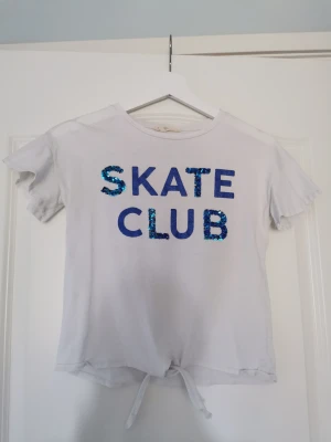 Croppad t-shirt med glitter och paljetter  - Fin croppad vit t-shirt med glitter och paljetter. Knyts där fram. Fint skick!