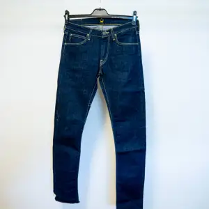 Jeans från Lee, herrmodell Luke. Slim fit. Mörkblå otvättad look. 99% bomull, 1% elastan.