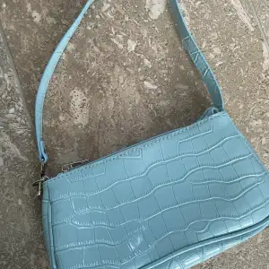 En oanvänd blå handväska 