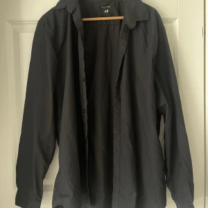 Skjorta - Helsvart skjorta från H&M i storlek XL! Fina knappar längst ner på varje arm! Hem och fin!