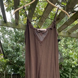 Brun klänning - Brun klänning med spetsdetaljer. Går att reglera axelbanden, skulle säga att den är storlek M. 