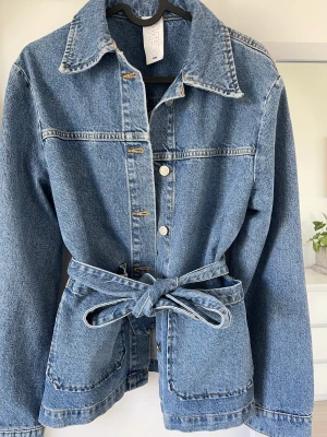 Jeansjacka med knytband - Säljer min fina jeansjacka då jag tappat bort kvittot och prislappen inte sitterkvar Aldrig använd och i nyskick:) Från Carin Wester inköpt från Åhléns!