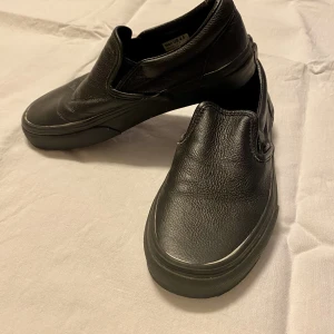 Vans slip in i svart skinn - Klassiska Vans slip in i svart skinn. Storlek US 4.5 (man) US 6 (kvinna). Fint skick.