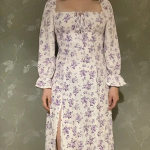 Blommig långklänning  - Superfin vit klänning med lila blommor, Stl M Slits på ena sidan och går ca2dm åvanför fotleden på mig som är 173cm